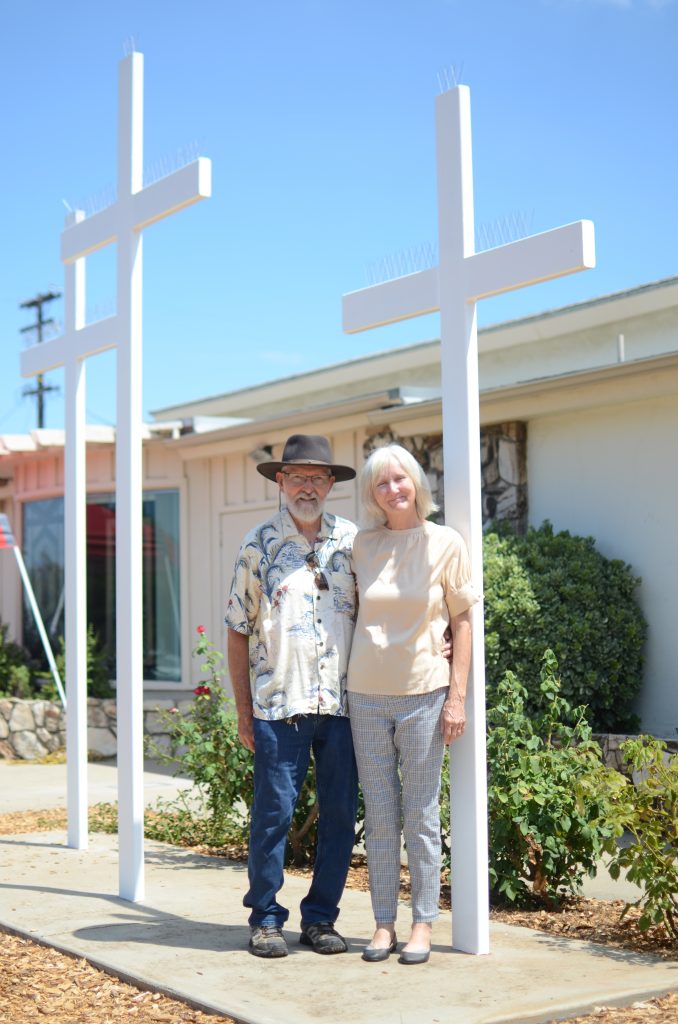 Linda and ___ Eastis, standing in front of a white cross.